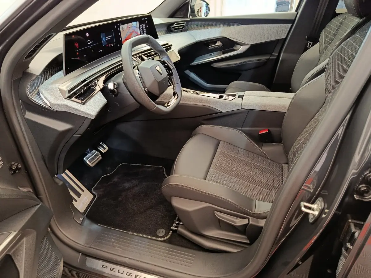Intérieur avant droit du Peugeot 3008 noir 2025, avec siège tissu-cuir, volant multifonction et écran tactile large.