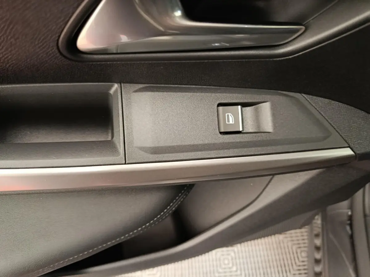 Détail de la commande de lève-vitre côté conducteur du Peugeot 3008 noir, avec garniture intérieure en cuir noir.