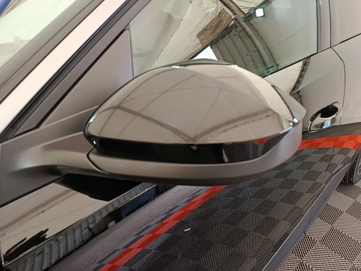 Rétroviseur droit noir brillant de la Peugeot 3008 1.2 Hybrid 145 GT, vue rapprochée avec reflet du plafond.