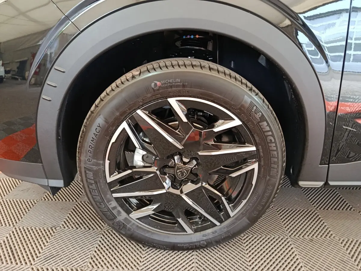 Gros plan sur la roue avant droite noire du Peugeot 3008 1.2 HYBRID 145 GT avec jante alliage bicolore et pneu Michelin.