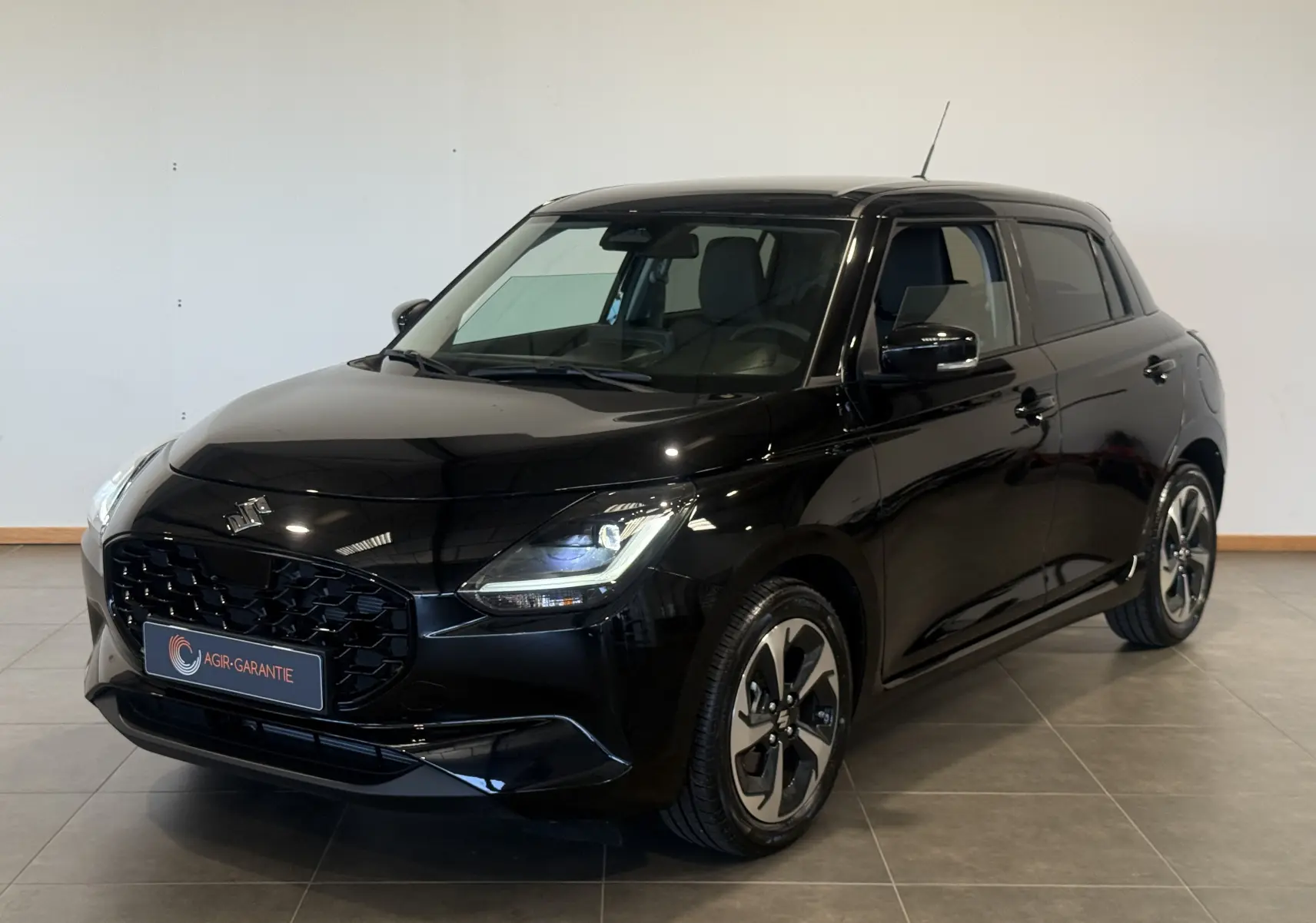 Suzuki Swift 2025 noire vue en 3/4 avant droit, avec calandre noire et jantes alliage distinctives.