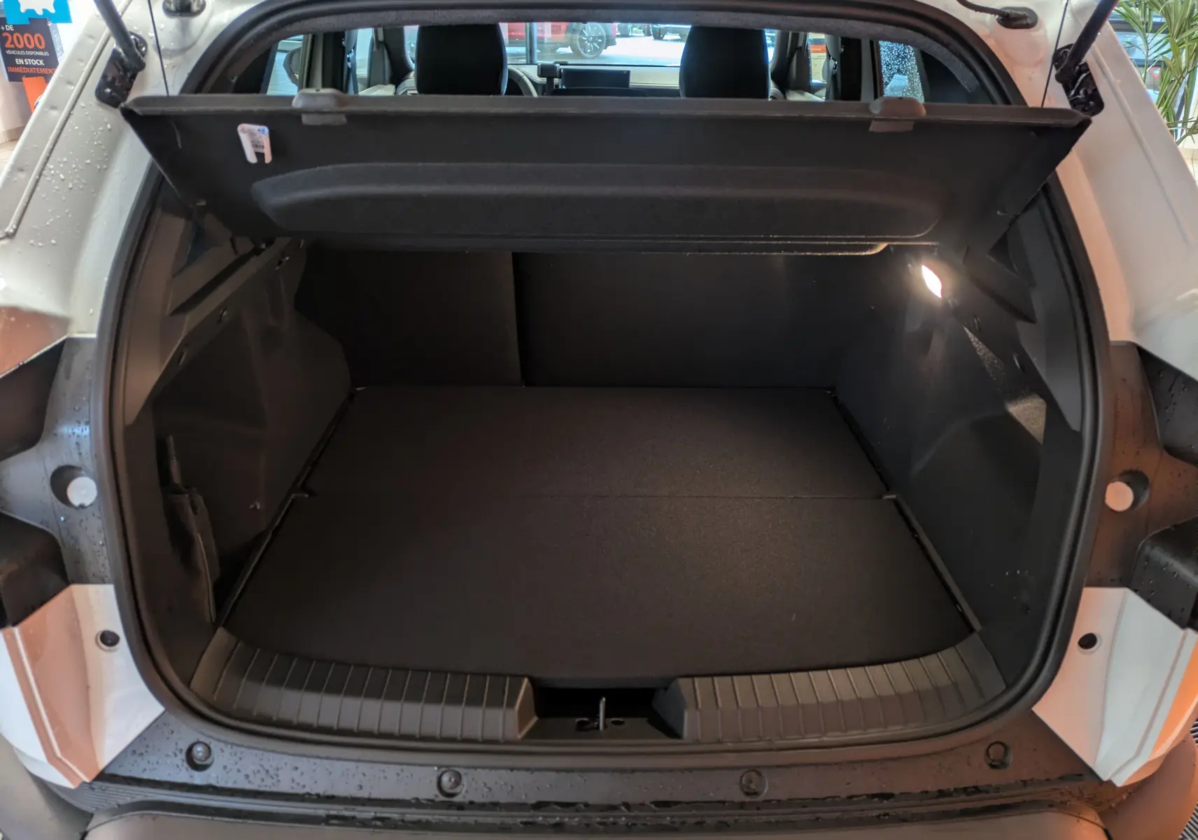 Coffre ouvert vu de l'arrière d'un Dacia Duster blanc glacier, montrant un espace de chargement propre et éclairé.