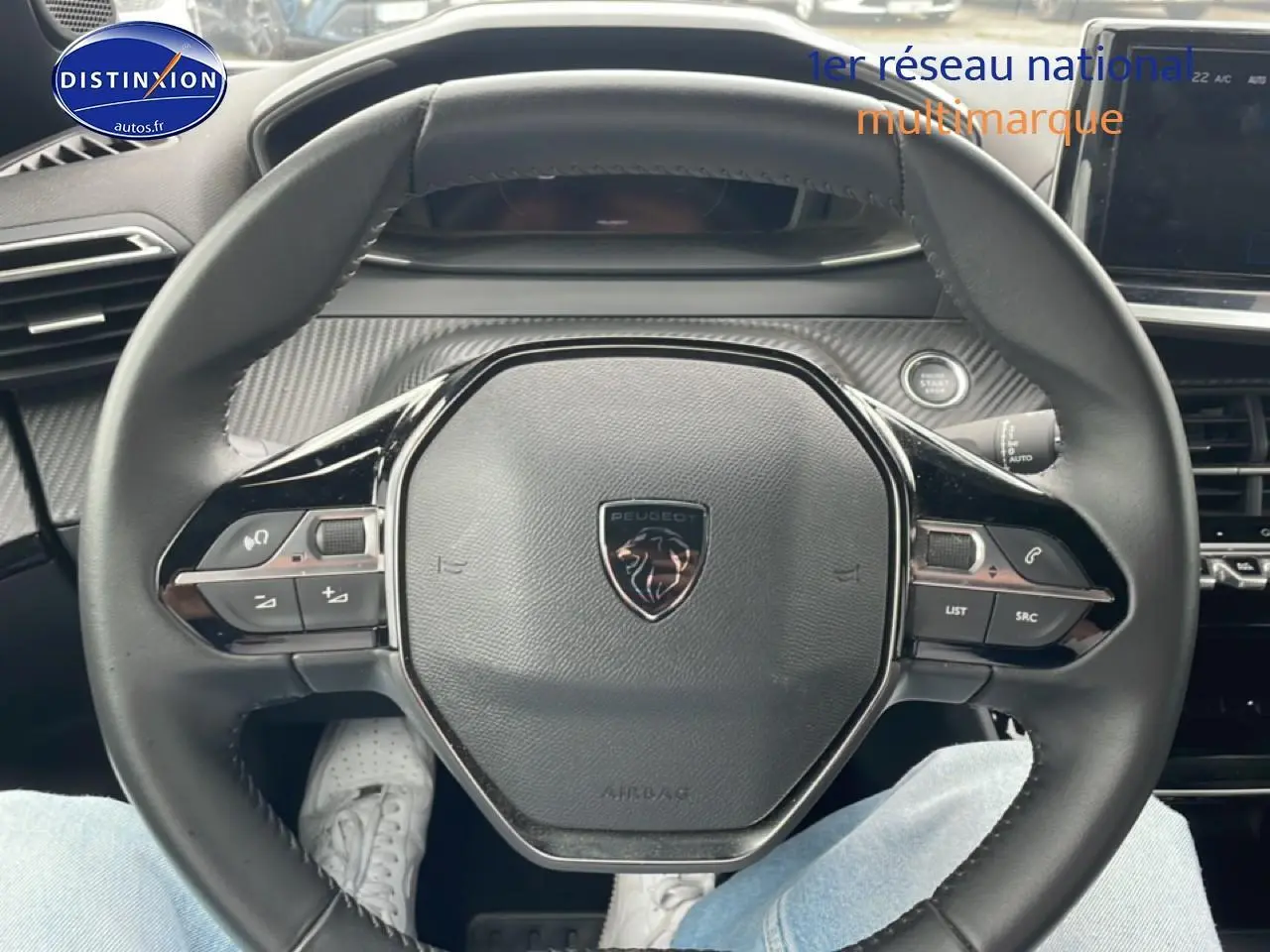 Vue rapprochée du volant multifonction noir avec logo Peugeot au centre dans l’habitacle du 2008 gris sellenium e.