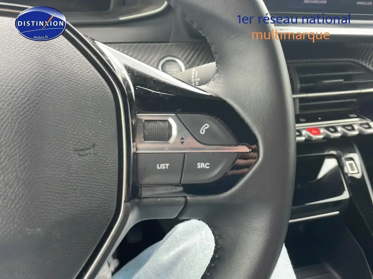 Gros plan sur le volant multifonction noir du Peugeot 2008 électrique 2025, avec commandes audio et téléphone intégrées.