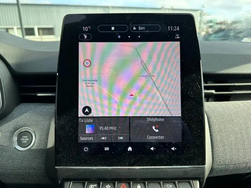 Écran tactile central de la Renault Clio 2025 affichant la navigation et la radio, intérieur avec bouton Start/Stop visible.