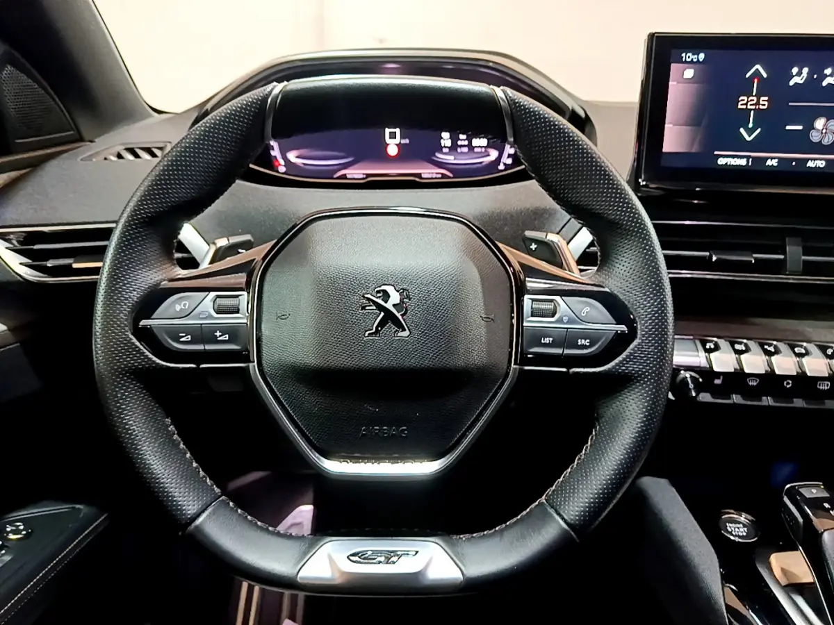 Vue rapprochée du volant cuir noir du Peugeot 3008 GT 2023 avec tableau de bord numérique et écran tactile central.