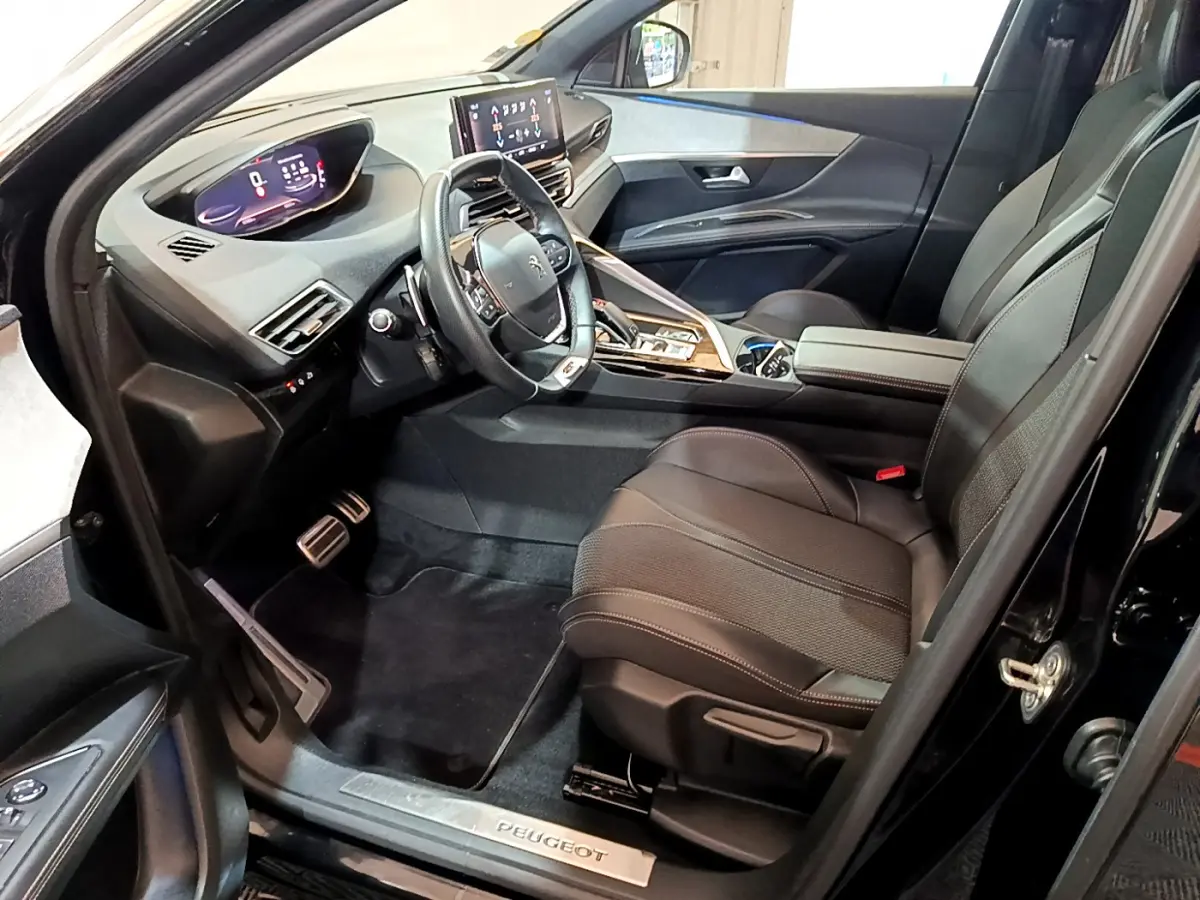 Vue intérieure côté conducteur du Peugeot 3008 noir 2023, mettant en valeur le tableau de bord digital et les sièges en cuir.