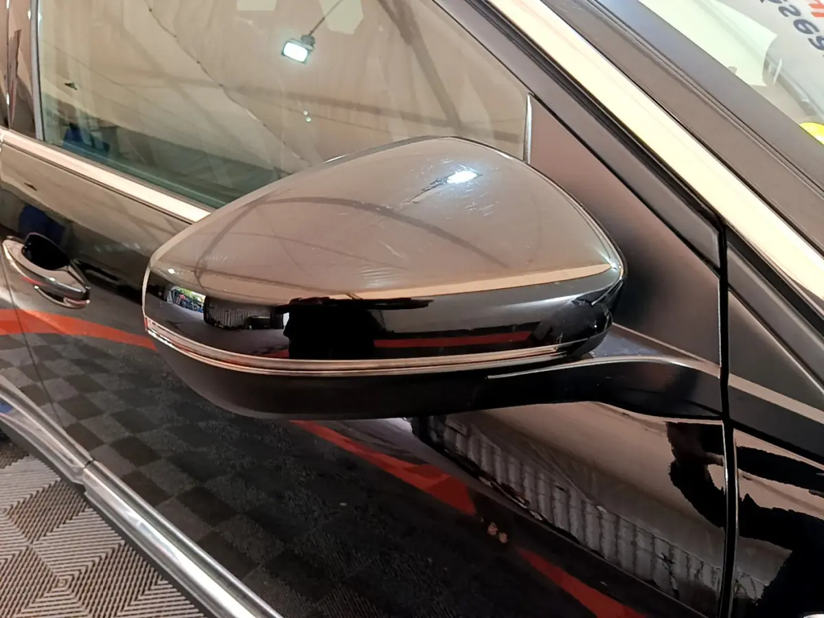 Gros plan sur le rétroviseur côté gauche noir brillant du Peugeot 3008 GT 2023 avec bande chromée fine.