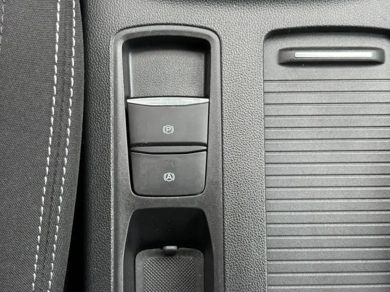 Gros plan sur la console centrale noire de la Ford Focus SW 2023, montrant les boutons du frein à main électronique et de l'arrêt automatique.
