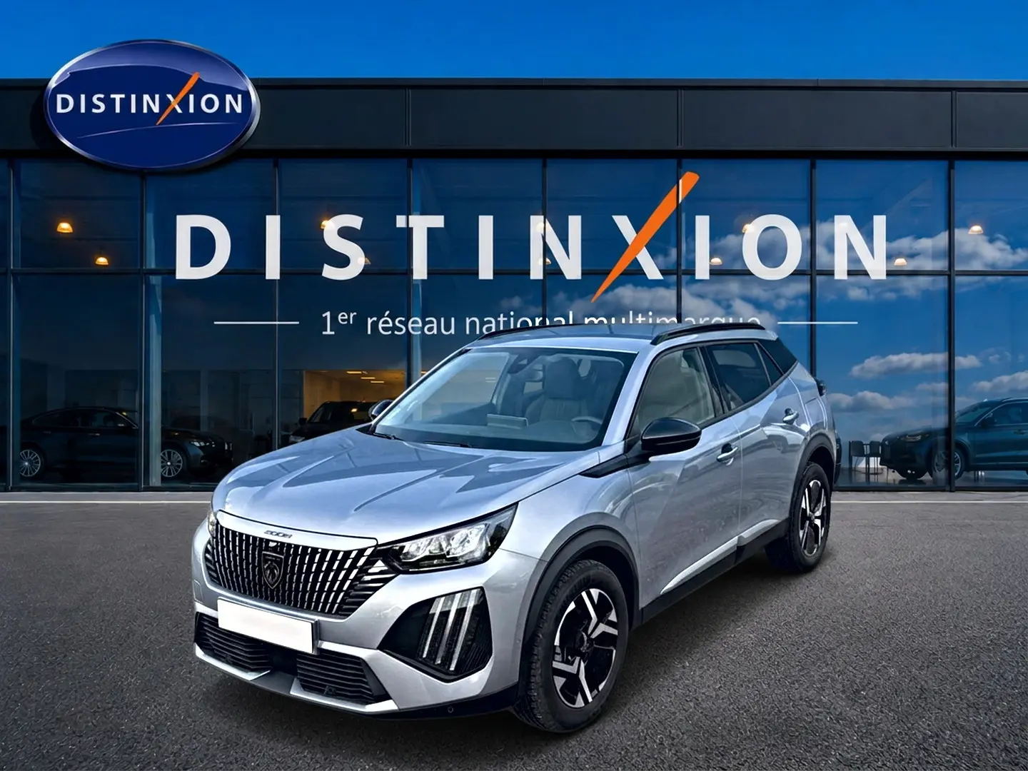 Peugeot 2008 gris artense en 3/4 avant droit devant une vitrine Distinxion, avec jantes alu et feux LED distinctifs.