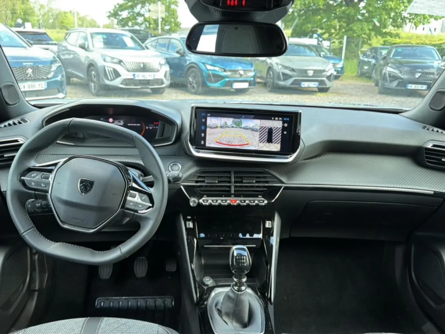 Vue intérieure avant du Peugeot 2008 gris Artense, avec tableau de bord moderne et écran tactile central affichant la caméra de recul.