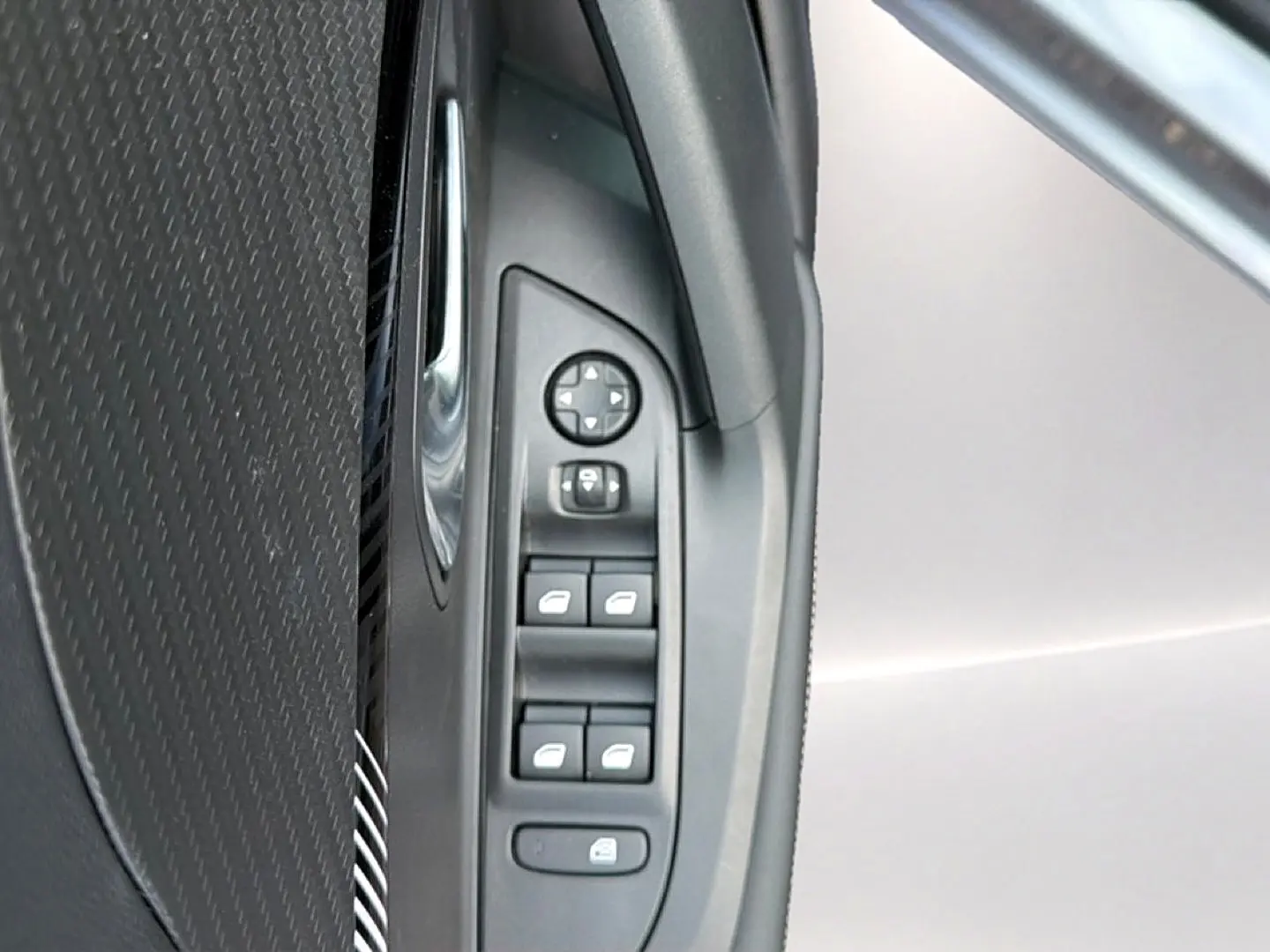 Vue rapprochée des commandes de lève-vitres et rétroviseurs côté conducteur du Peugeot 2008 gris Artense.