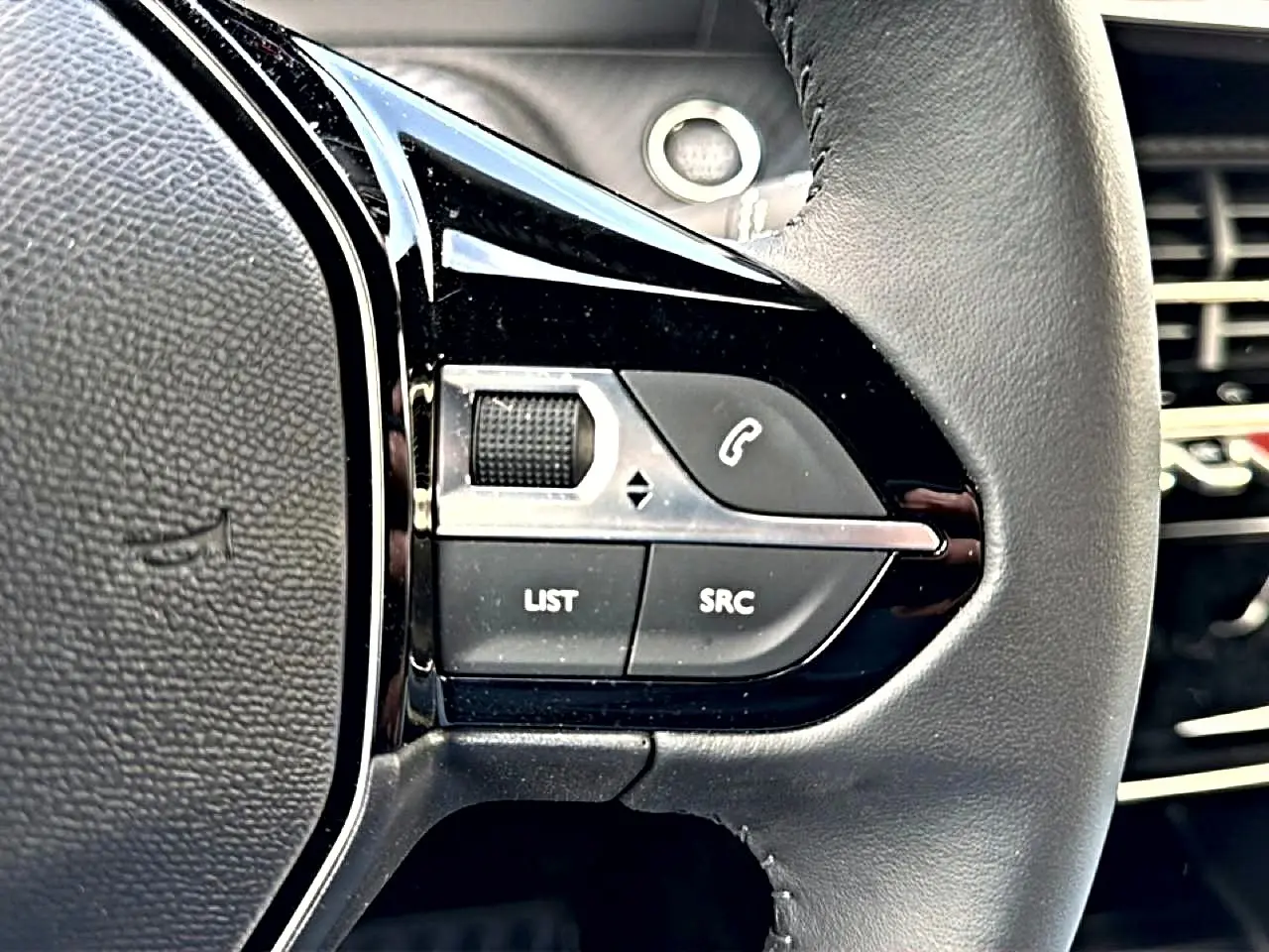 Gros plan sur les commandes noires du volant multifonction du Peugeot 2008 1.2 100 Allure gris Artense.