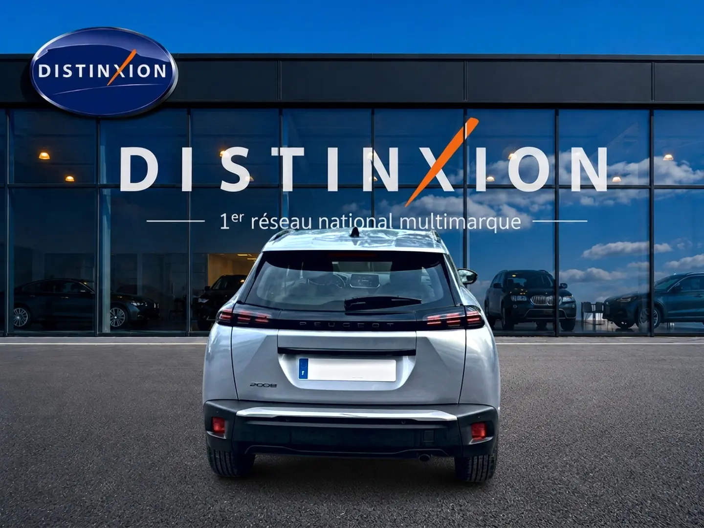 Vue arrière d'un Peugeot 2008 gris artense 2025 garé devant une vitrine avec logo Distinxion.