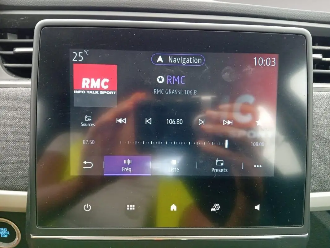 Écran tactile central de la Renault ZOE violet, affichant la radio RMC à 10:03, vue rapprochée de l’intérieur.