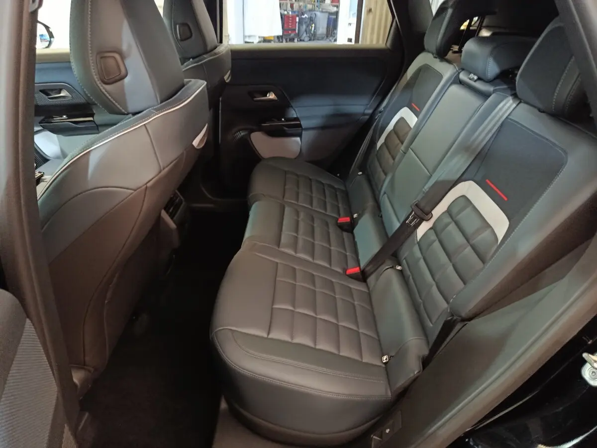 Vue intérieure côté droit des sièges arrière en cuir noir du Citroën C5 Hybride 2026 avec détails gris et rouges.