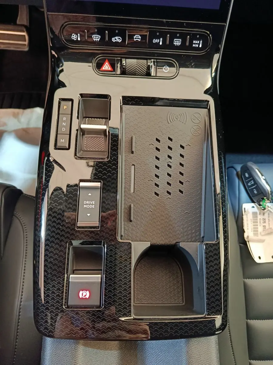 Vue plongeante sur la console centrale noire brillante du Citroën C5 Hybride 2026 avec commandes et recharge sans fil.