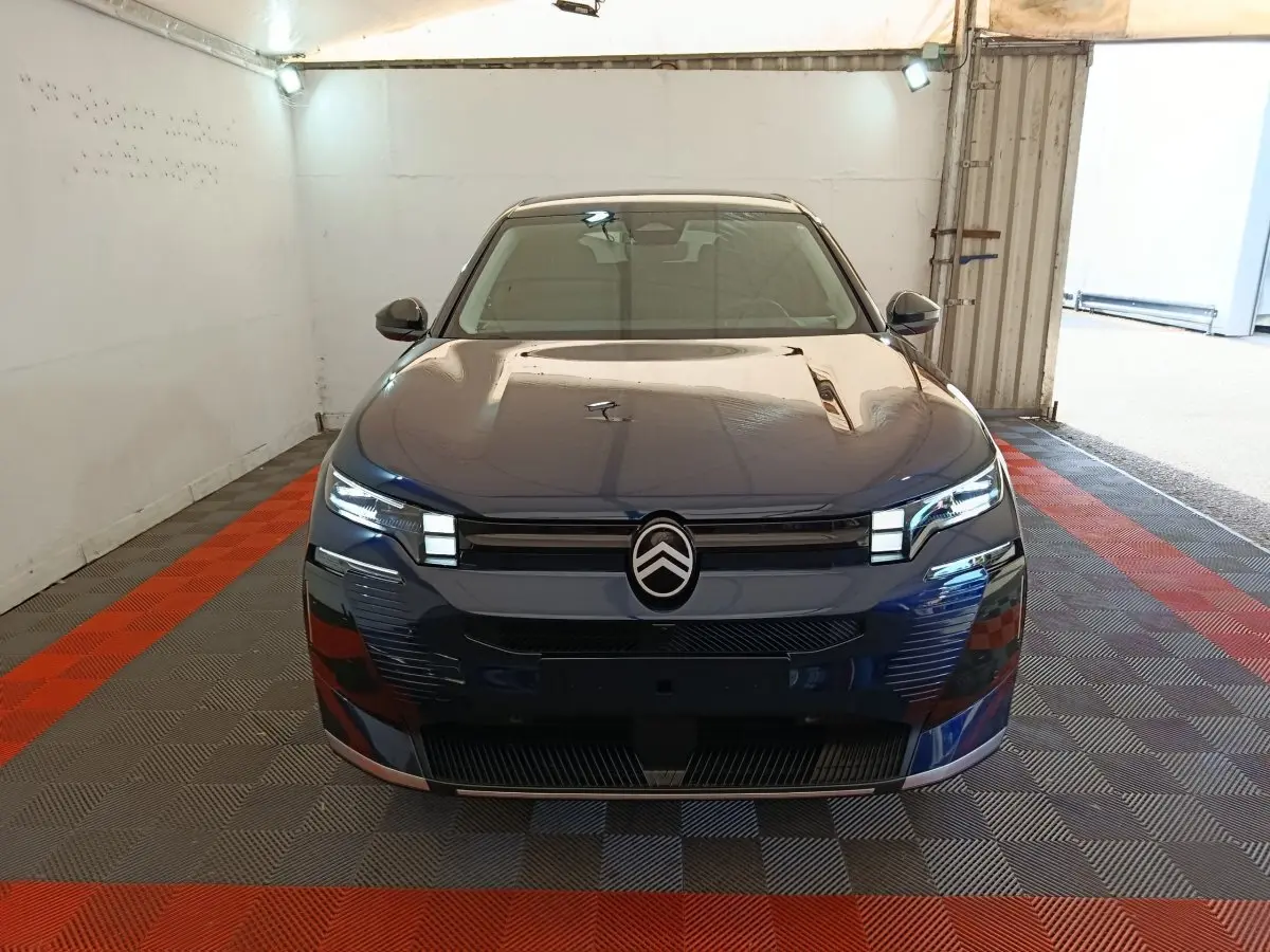 Vue frontale d'une Citroën C5 hybride bleu foncé avec phares LED et logo distinctif au centre de la calandre.