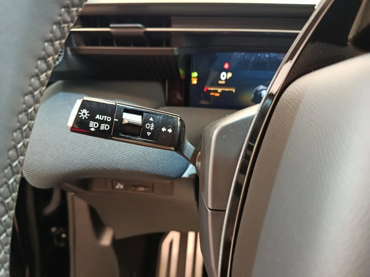 Gros plan sur la commande des feux à gauche du volant dans l’habitacle gris d’une Citroën C5 Hybride bleue 2026.