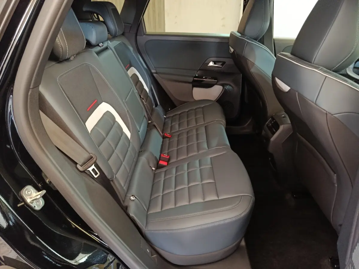 Vue côté gauche des sièges arrière en cuir noir avec surpiqûres blanches et détails rouges dans une Citroën C5 Hybride 2026.