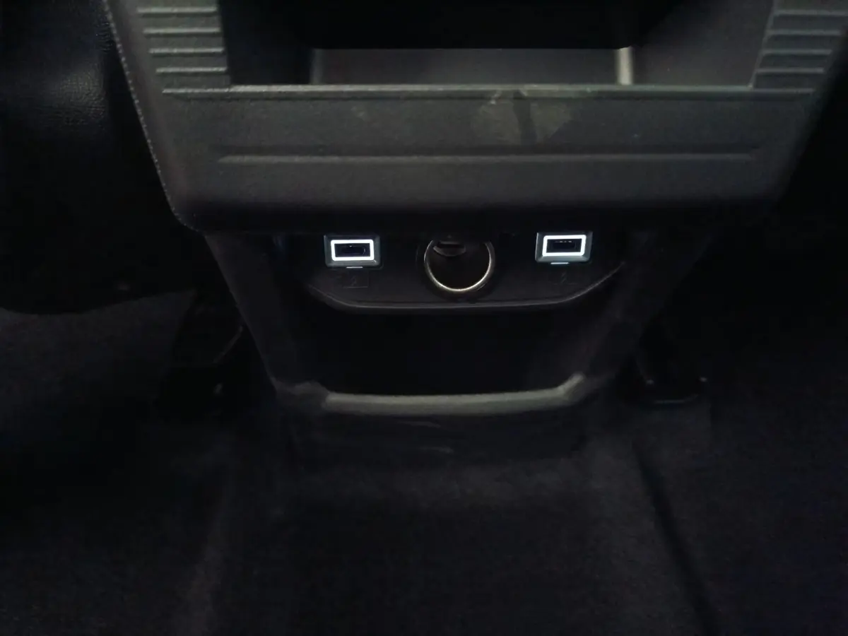 Prise USB arrière et prise 12V visibles sous la console centrale noire du Citroën C5 hybride 2026.