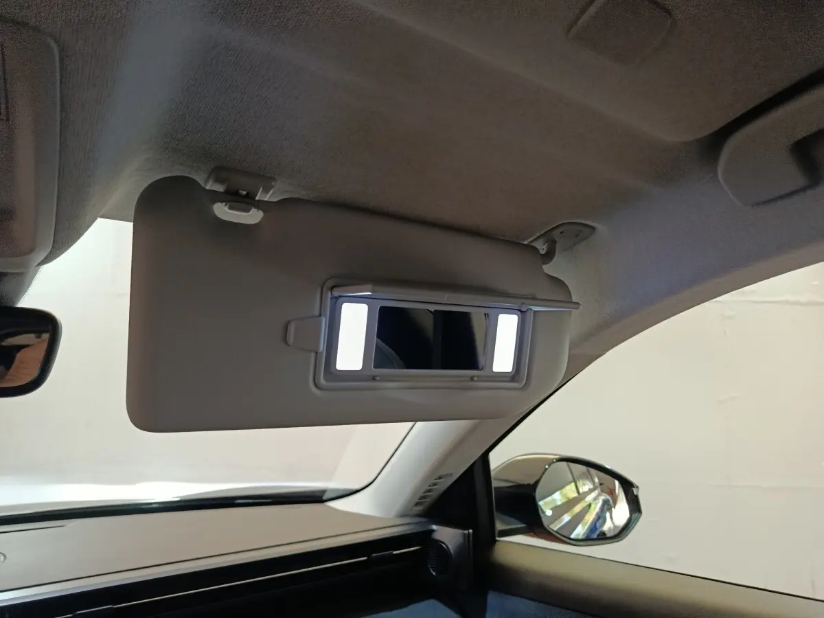 Intérieur du Citroën C5 Hybride bleu 2026, vue côté passager sur le pare-soleil avec miroir éclairé et rétroviseur.