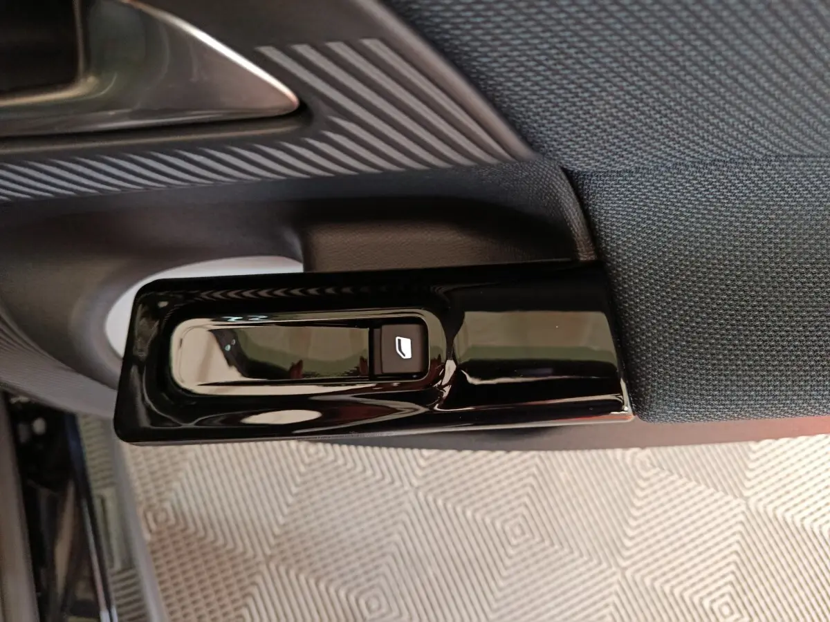 Gros plan sur la commande de lève-vitre côté gauche de la porte intérieure d’une Citroën C5 Hybride bleue 2026.