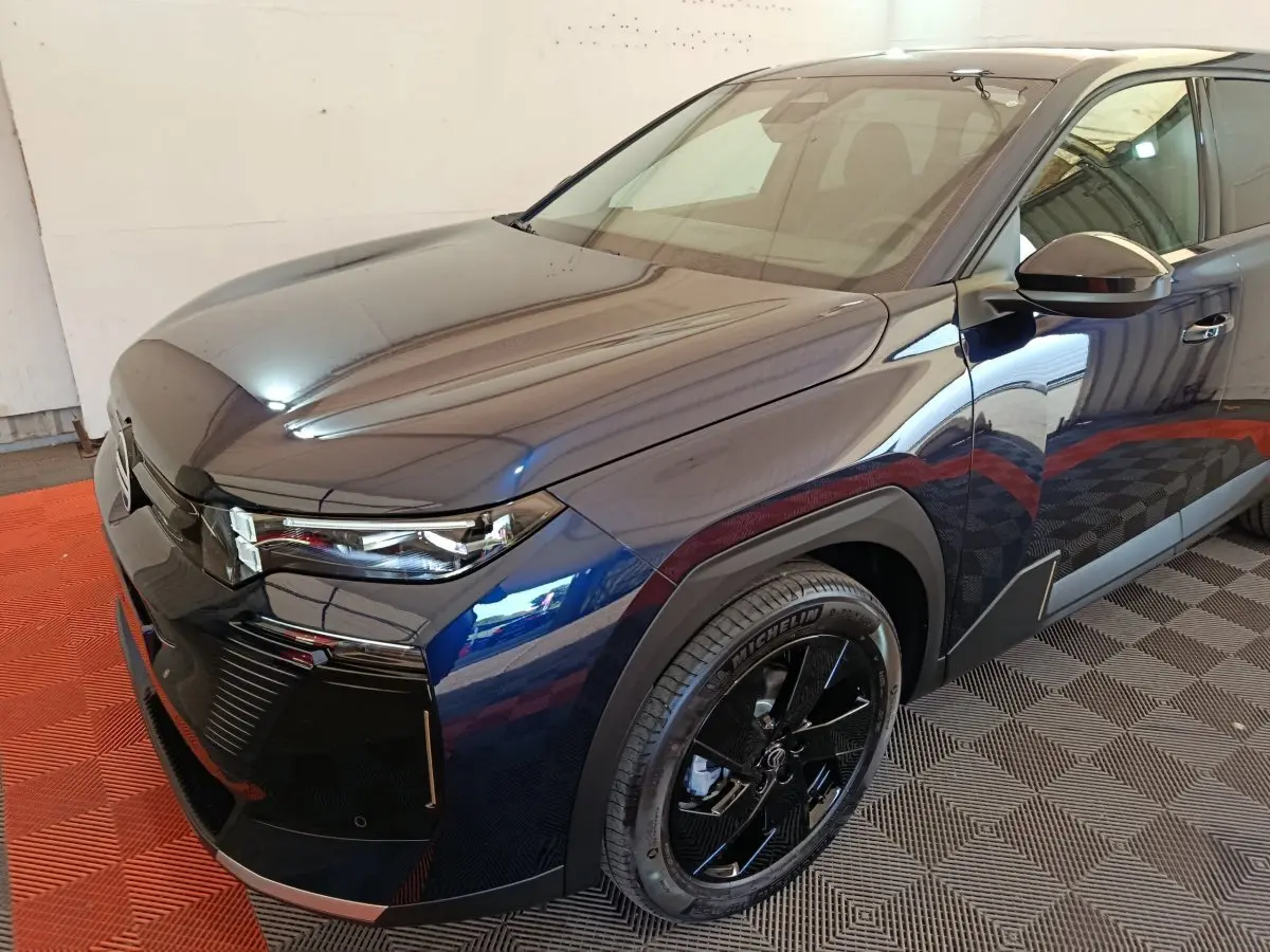 Vue 3/4 avant droit d'une Citroën C5 hybride bleu foncé avec jantes noires et phares LED distinctifs.