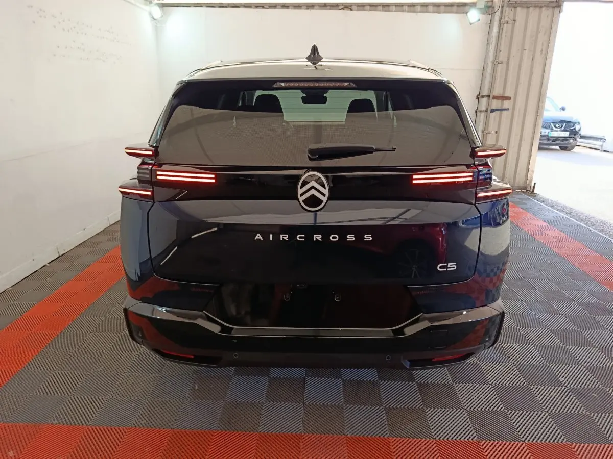 Vue arrière d'une Citroën C5 Aircross bleu foncé avec feux LED horizontaux allumés dans un garage.