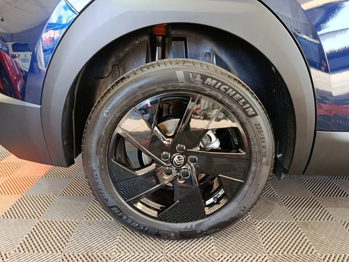Gros plan sur la roue avant droite bleue d’une Citroën C5 Hybride avec jante noire brillante et pneu Michelin.