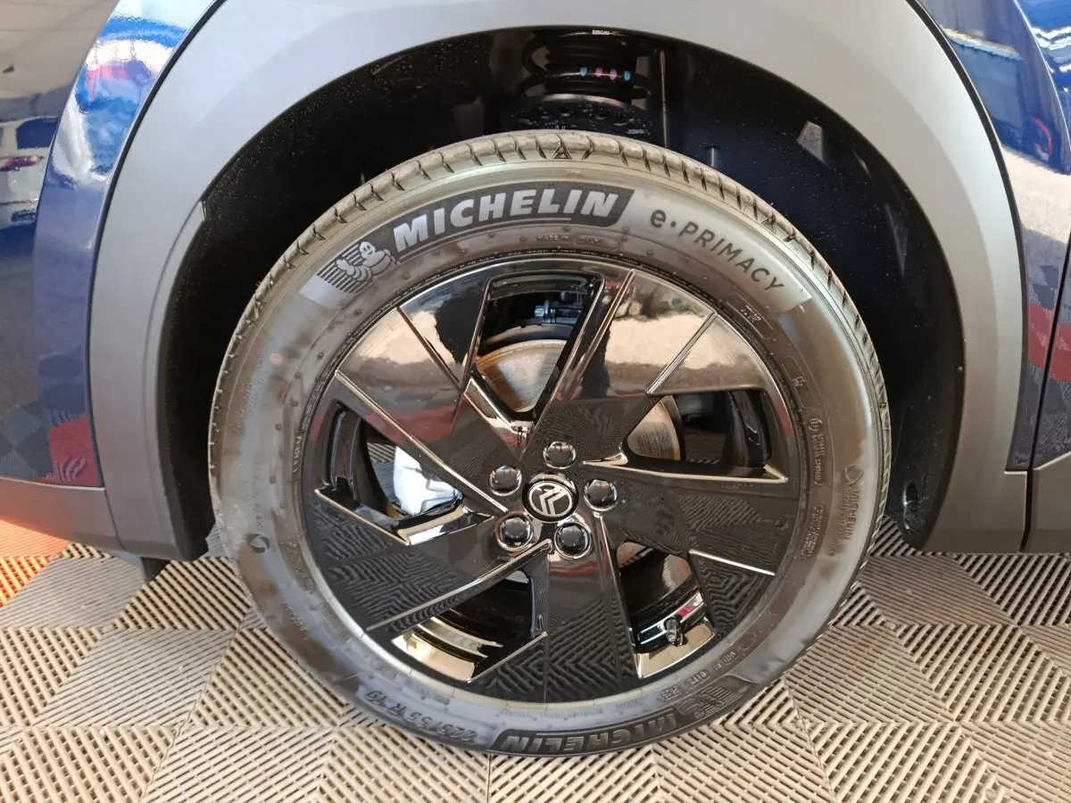 Gros plan sur la roue avant droite d'une Citroën C5 hybride bleu, avec jante noire brillante et pneu Michelin.
