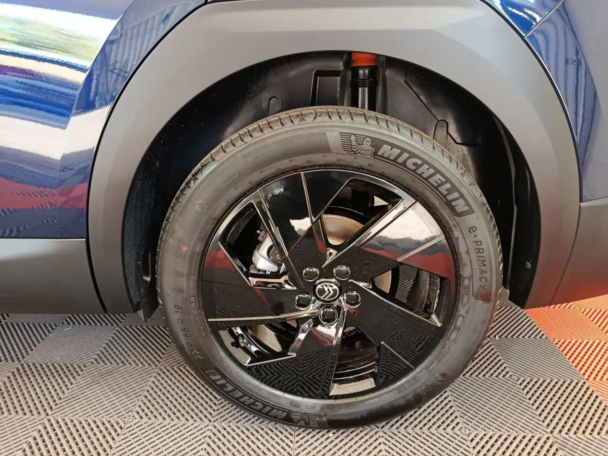Gros plan sur la roue avant droite noire brillante d'une Citroën C5 Hybride bleu, avec pneu Michelin visible.