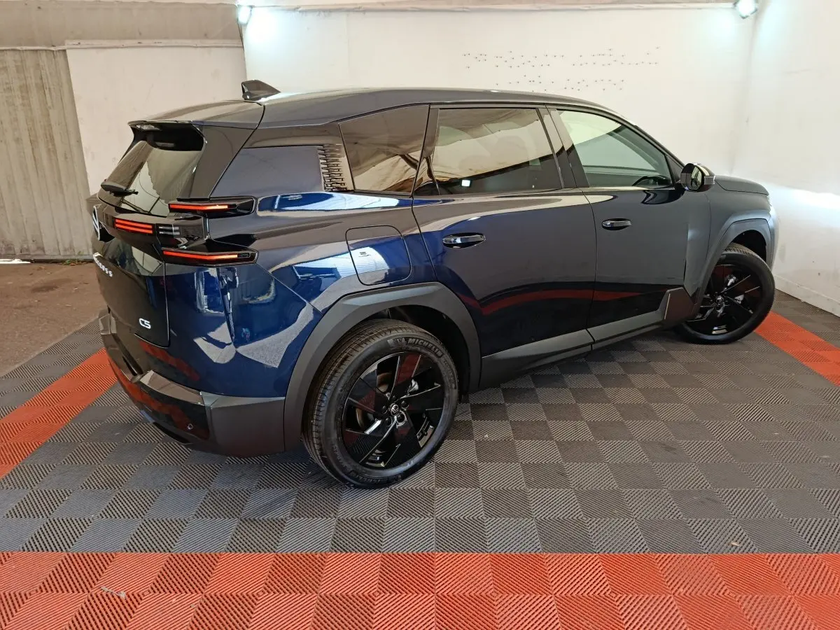Vue 3/4 arrière droite d'une Citroën C5 hybride bleu foncé avec jantes noires et feux arrière LED distinctifs.