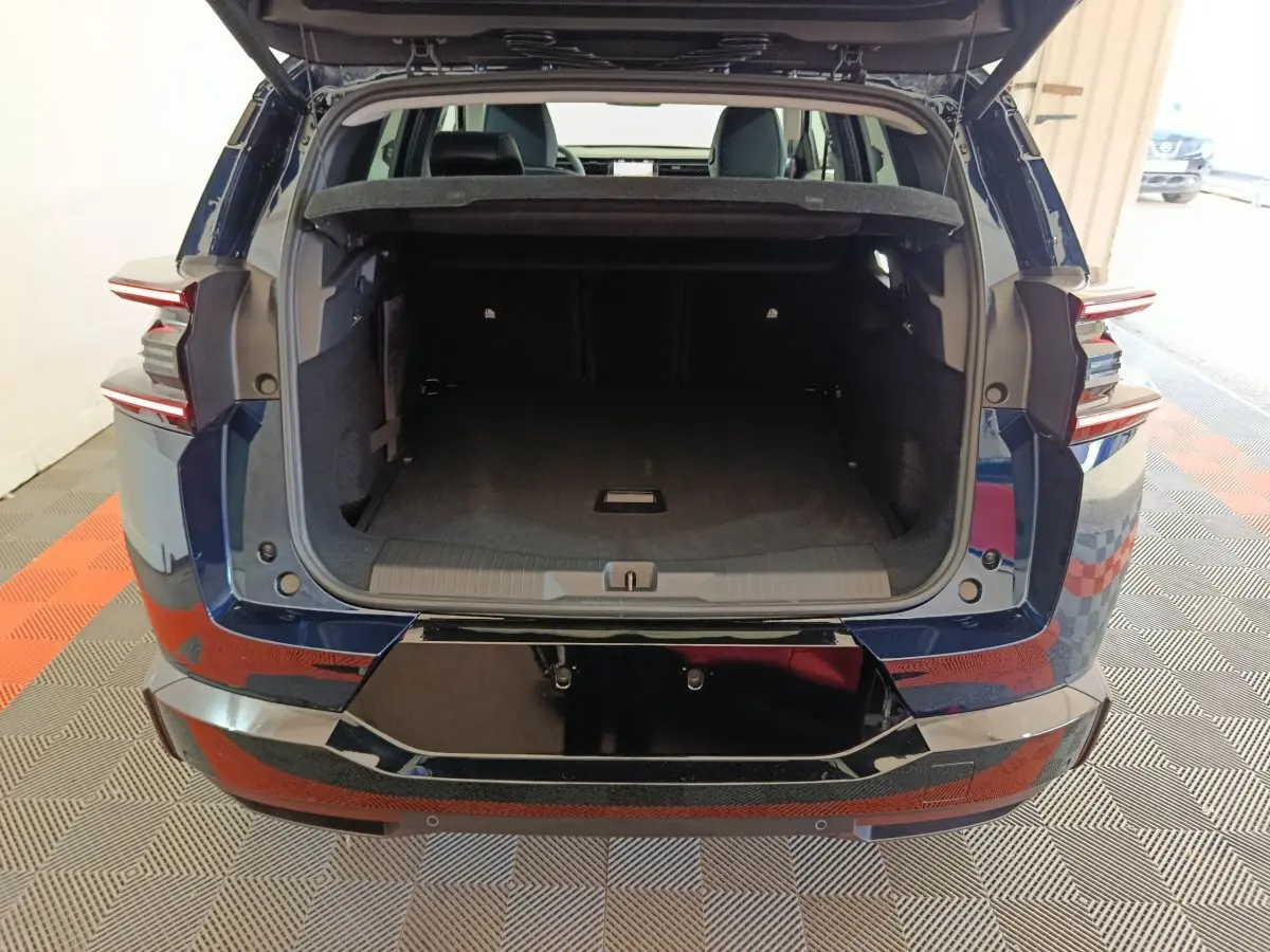 Coffre ouvert d'une Citroën C5 Hybride bleu vue arrière, avec feux arrière LED et seuil de coffre noir brillant.