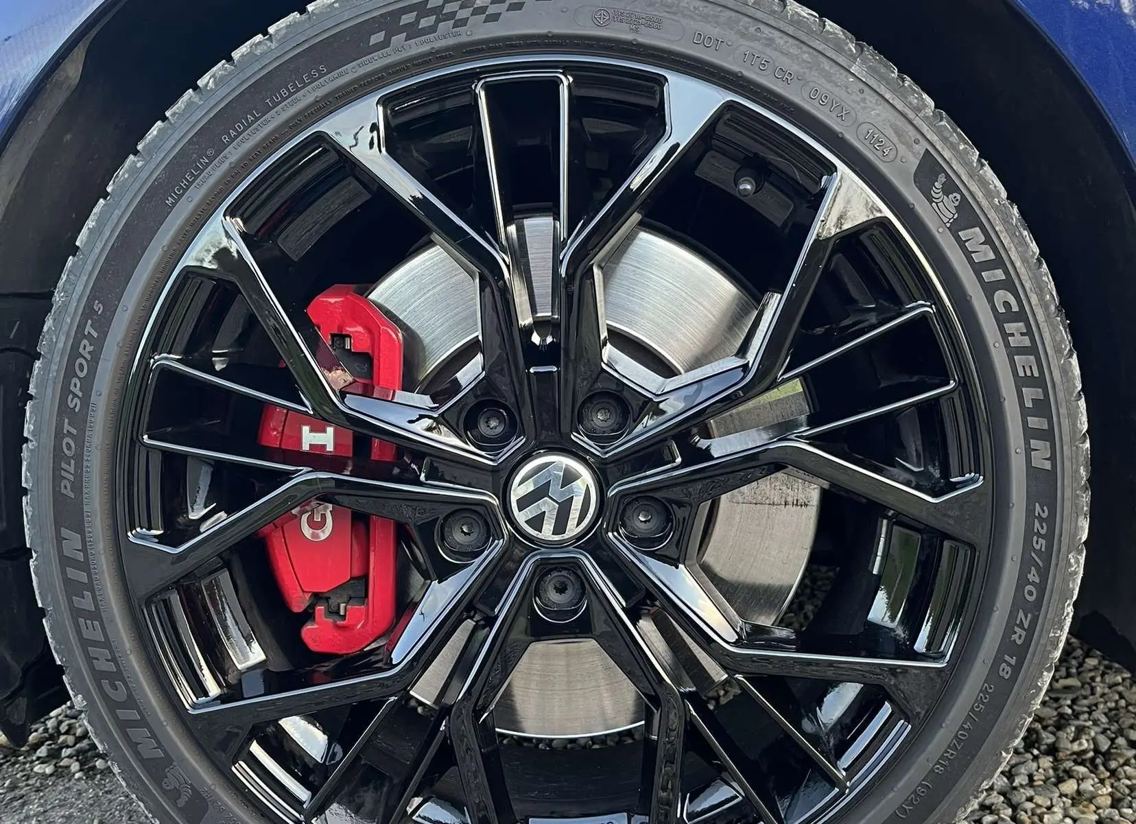 Gros plan sur la roue avant gauche d'une Volkswagen Golf GTI Performance bleu lapiz, jante noire brillante et étrier rouge.