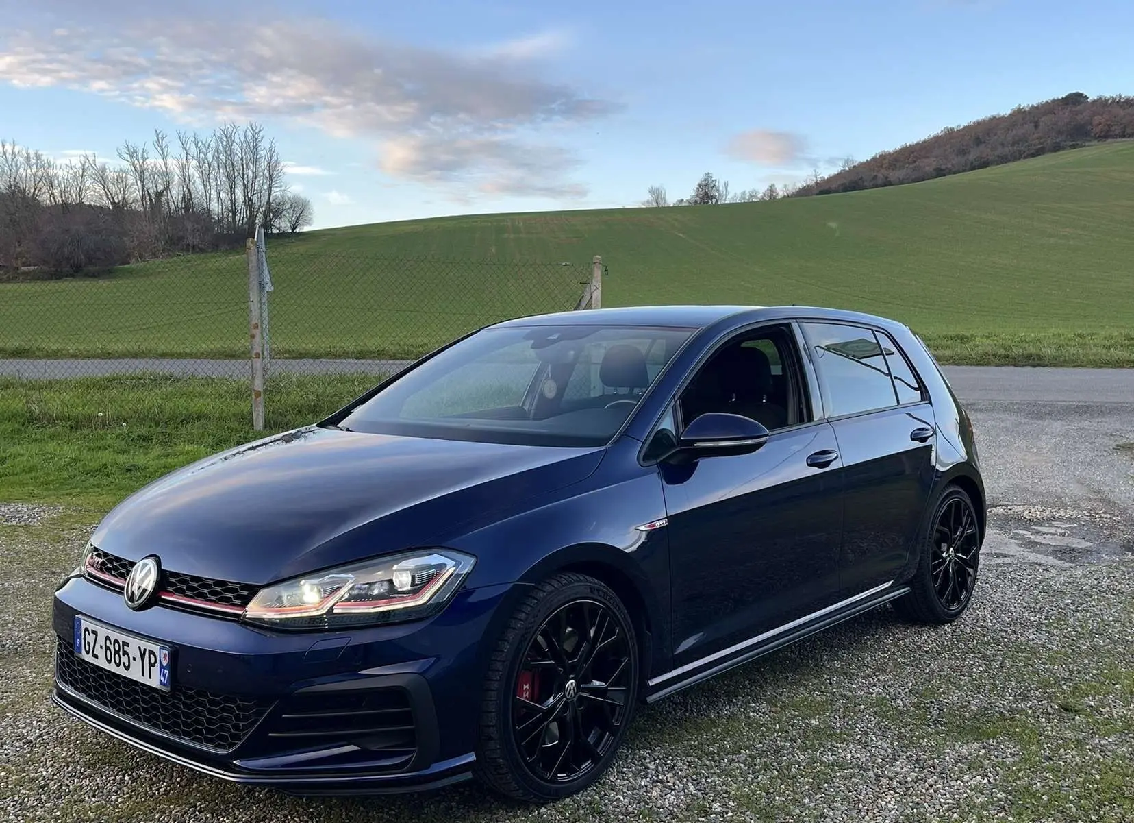 Volkswagen Golf VII GTI Performance bleu lapiz métal vue 3/4 avant droit avec jantes noires et calandre rouge