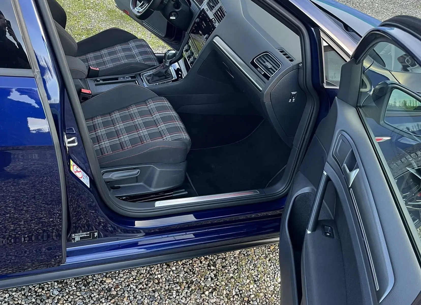 Intérieur côté conducteur d'une Volkswagen Golf VII bleu lapiz, sièges à motif tartan et tableau de bord moderne.