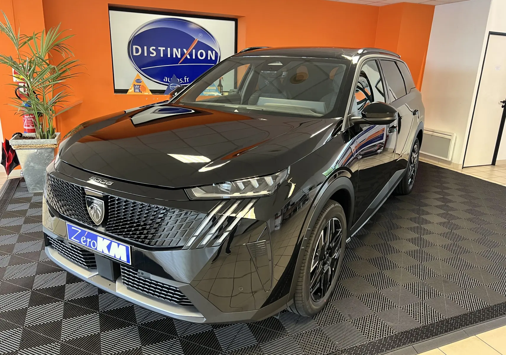 Vue 3/4 avant droite du Peugeot 5008 noir hybride 2025 avec calandre distinctive et jantes alliage 19 pouces.