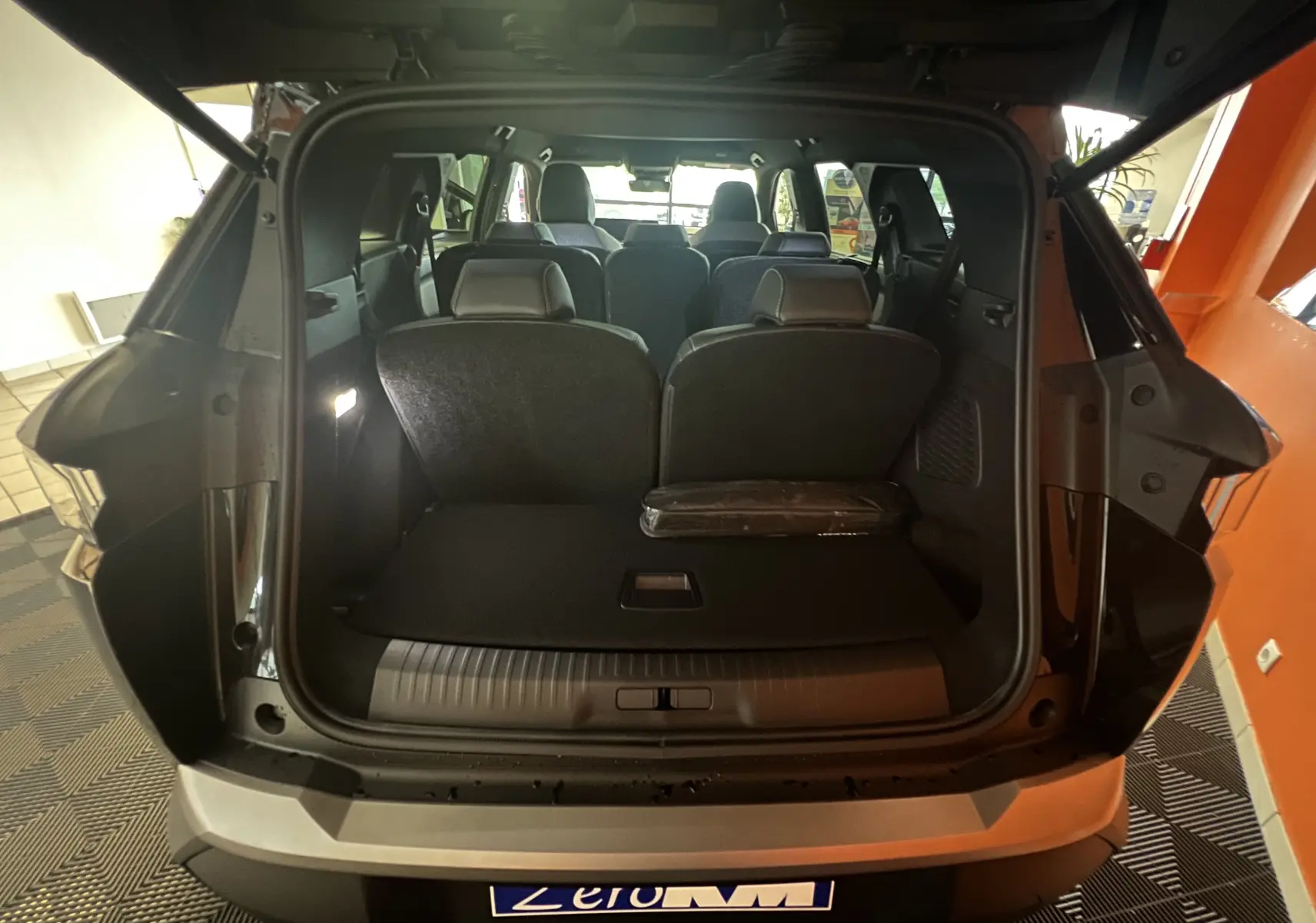 Coffre ouvert vue arrière d'un Peugeot 5008 noir 2025, montrant les sièges arrière et l'espace de chargement.