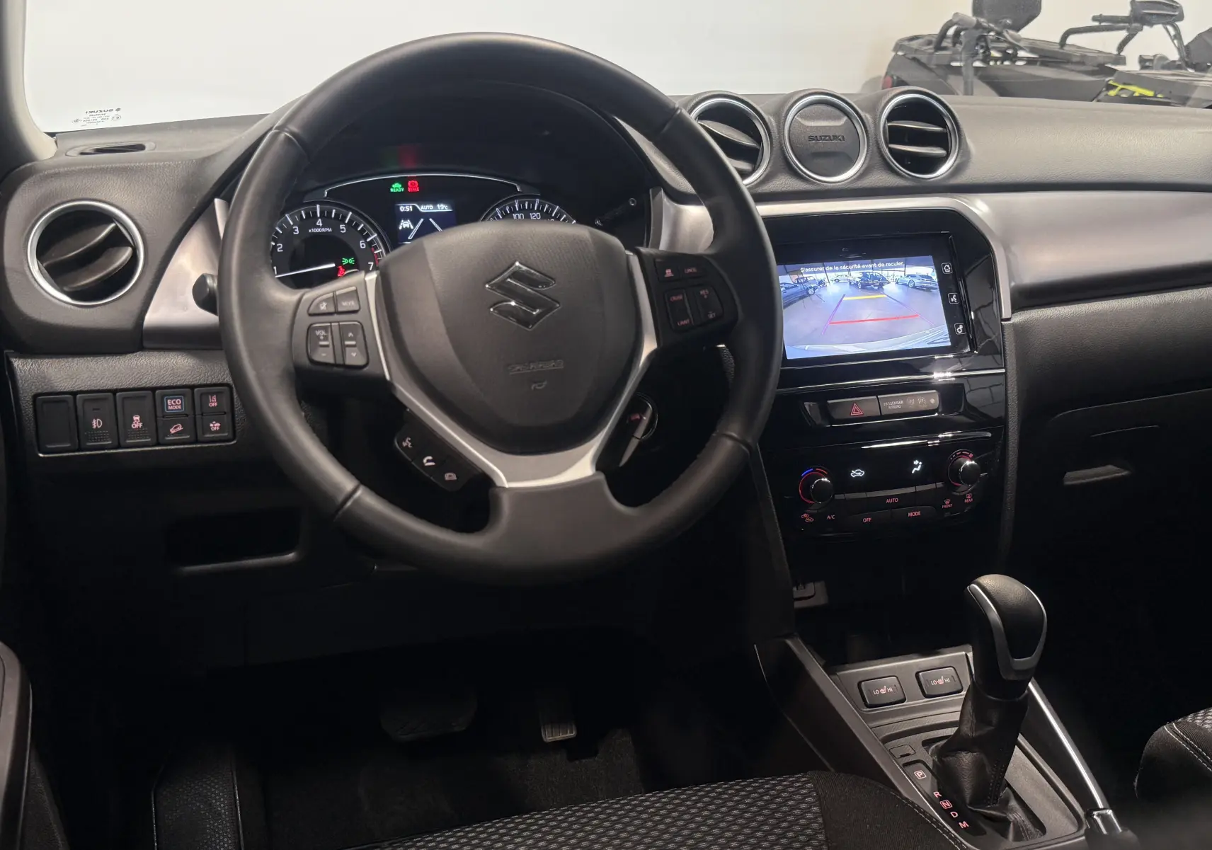Vue intérieure du tableau de bord du Suzuki Vitara beige 2023, avec volant multifonction et écran tactile affichant la caméra de recul.