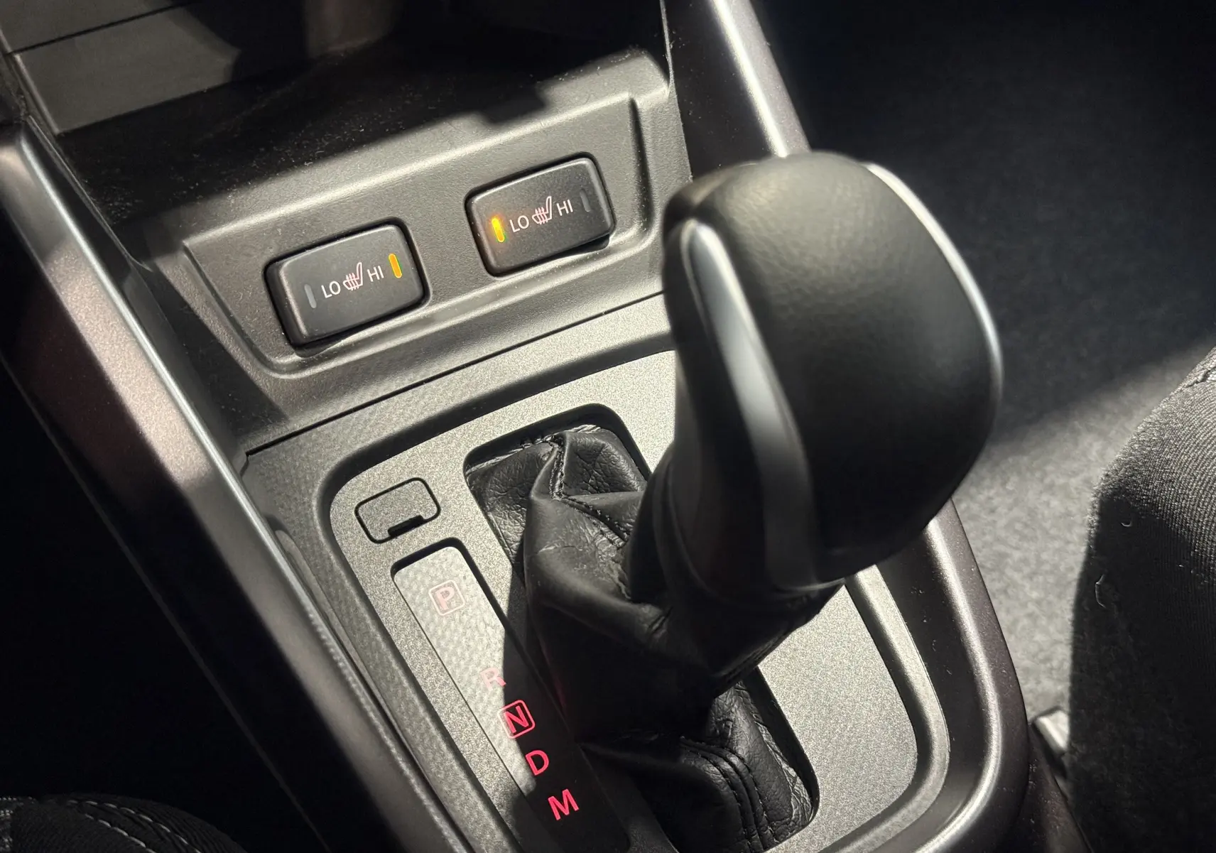 Le levier de vitesses automatique et les commandes de sièges chauffants du Suzuki Vitara beige 2023 vus de près.