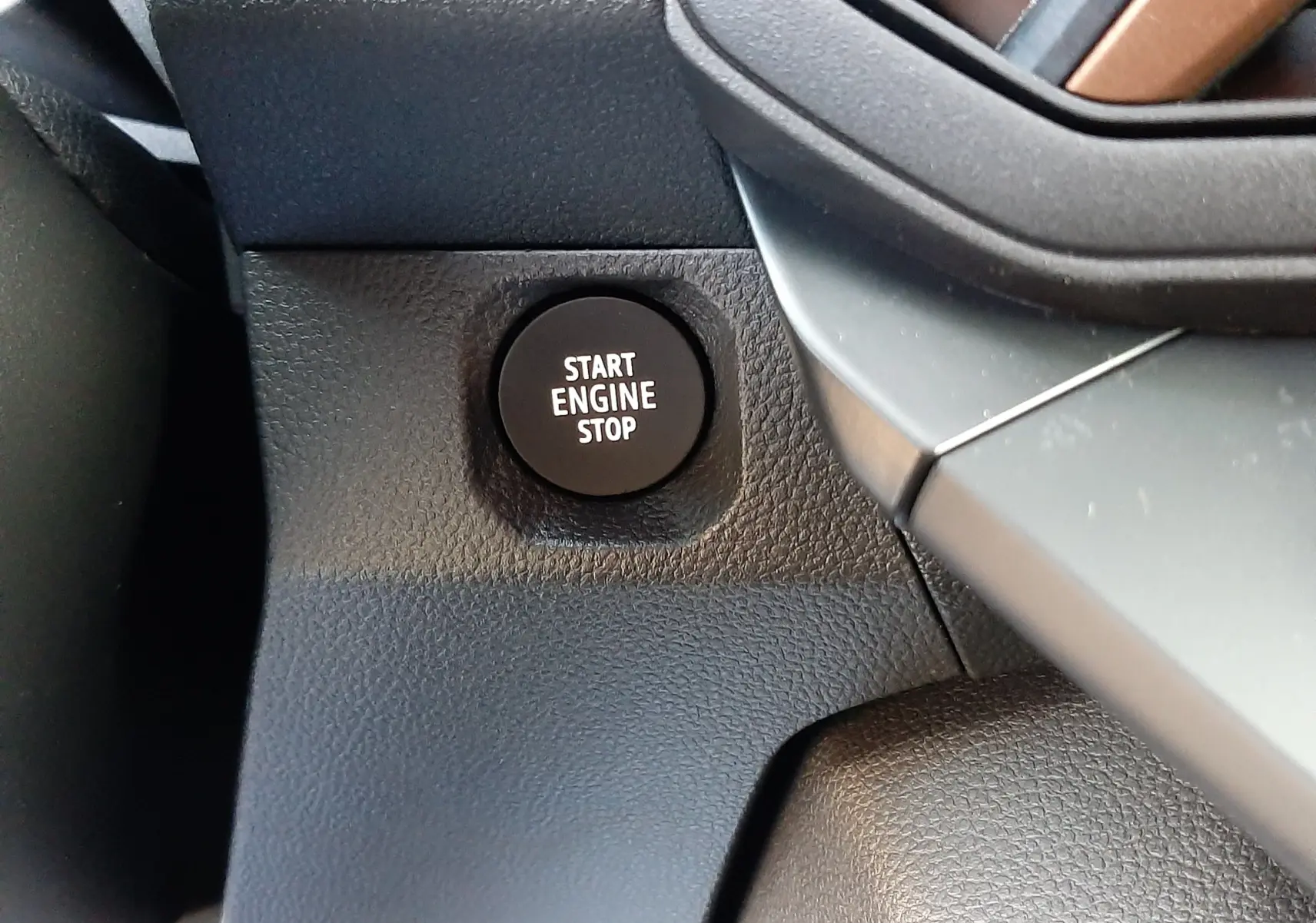 Gros plan sur le bouton Start Engine Stop du tableau de bord du Dacia Duster 1.6 Hybrid 140ch Sandstone 2025.