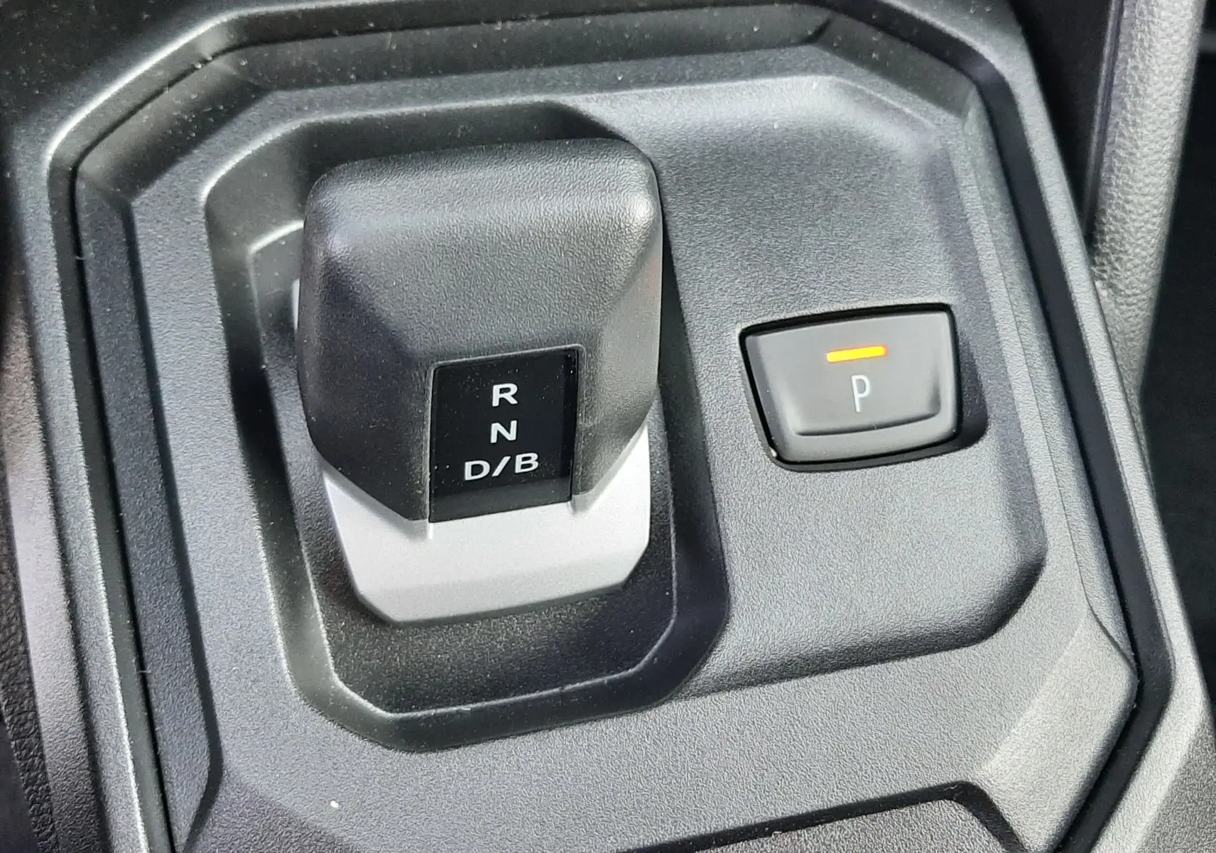 Gros plan sur le levier de vitesses automatique et bouton parking du Dacia Duster 1.6 Hybrid 140ch couleur Sandstone.