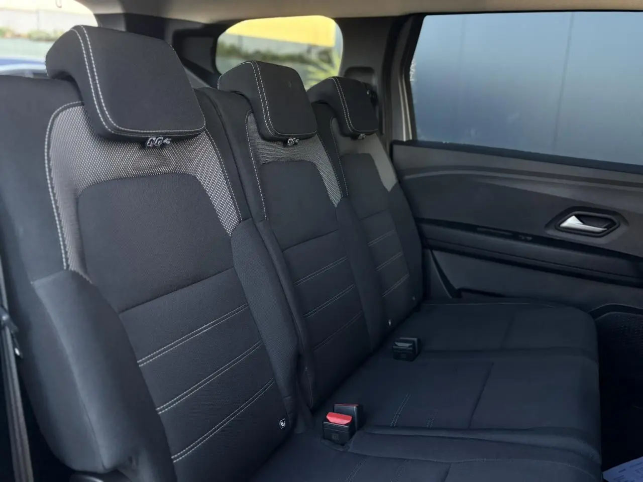 Vue latérale intérieure des sièges arrière noirs du Dacia Jogger 2025, finition Expression avec surpiqûres blanches.