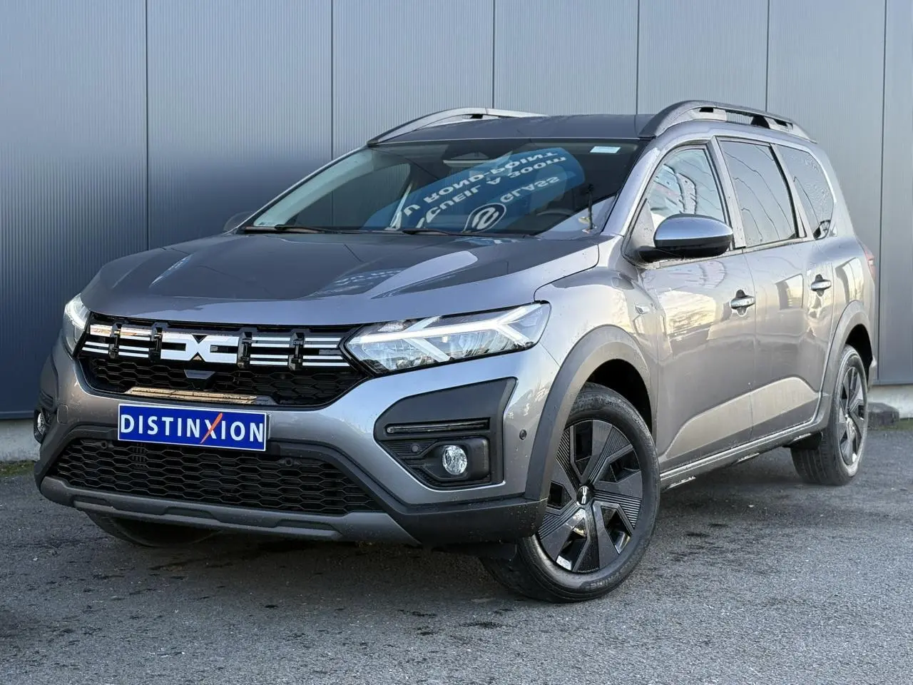 Vue 3/4 avant d'un Dacia Jogger Gris Schiste avec calandre noire et jantes noires distinctives.