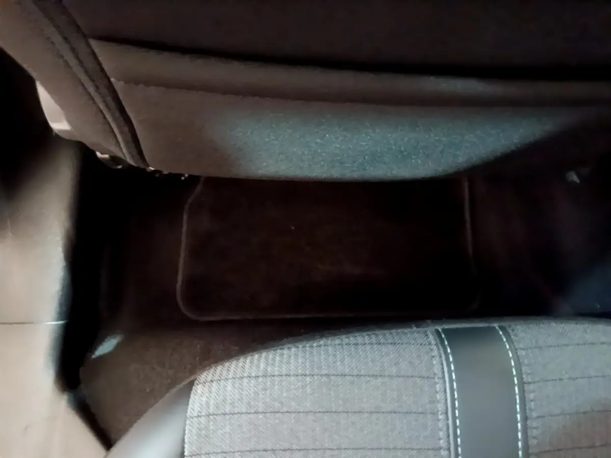 Vue plongeante sur le sol et l'assise arrière droite de la Peugeot 208 jaune, montrant la moquette et le tissu du siège.