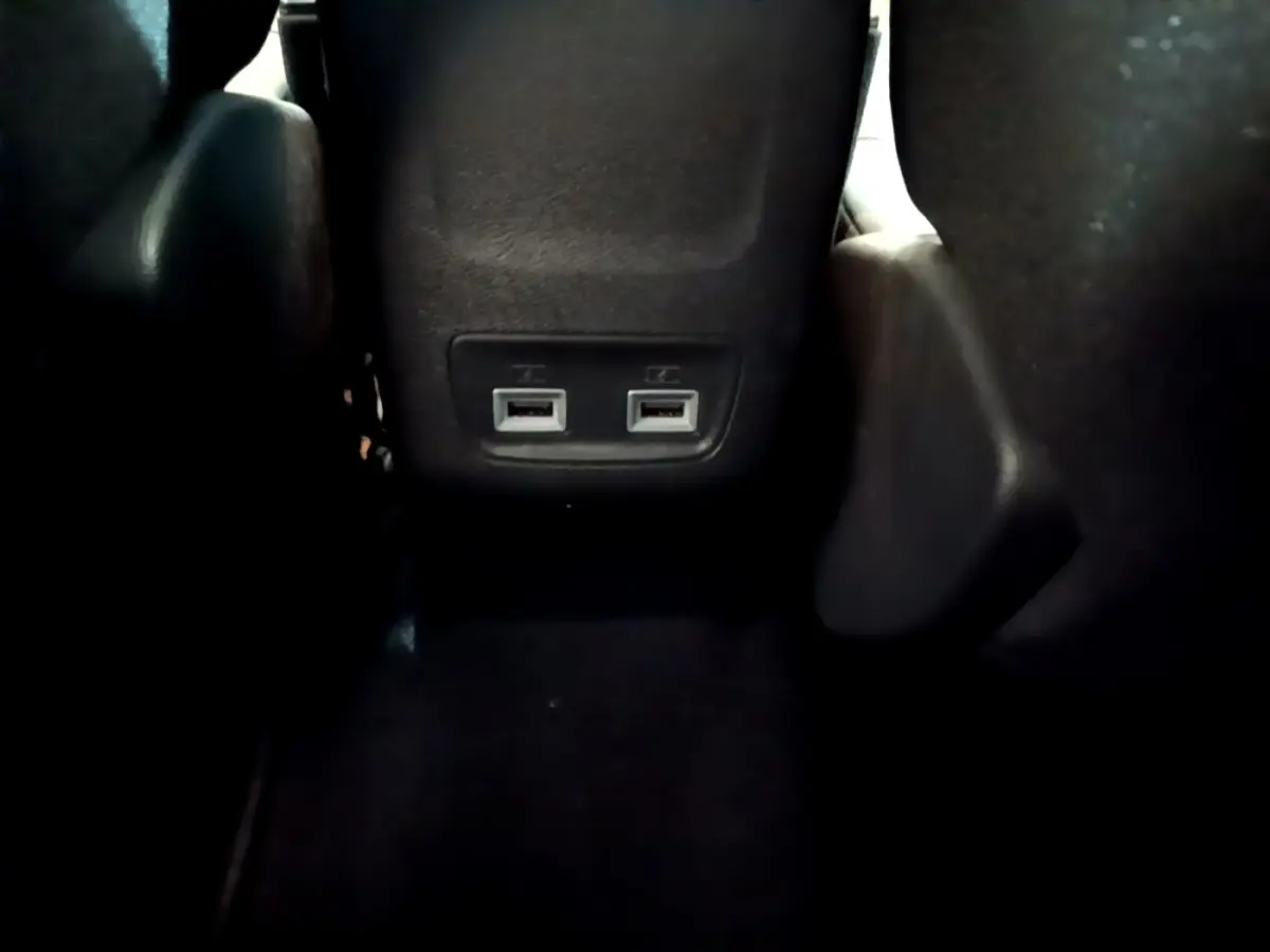 Prise USB double vue en gros plan à l'arrière des sièges noirs de la Peugeot 208 jaune 2023.