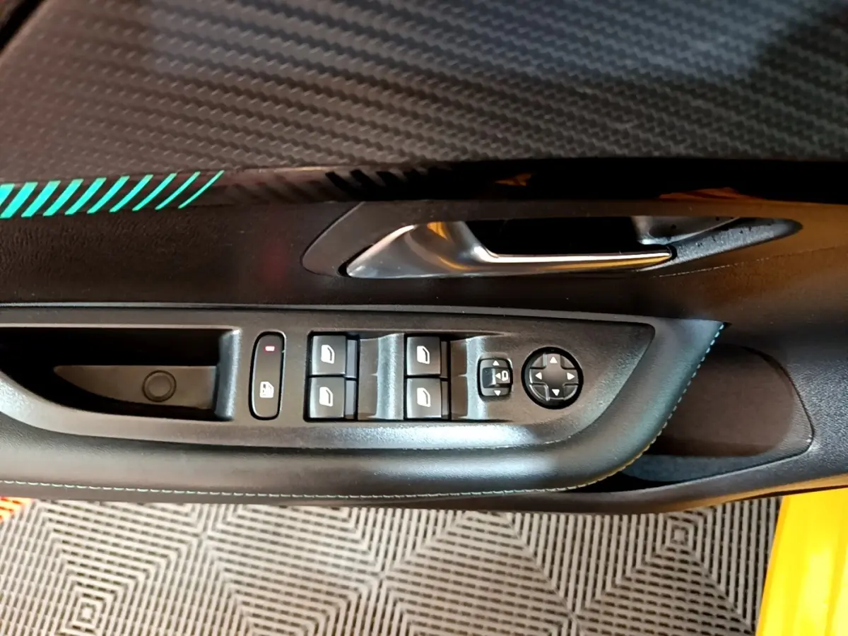 Gros plan sur la commande des vitres et rétroviseurs côté conducteur d'une Peugeot 208 jaune 2023.