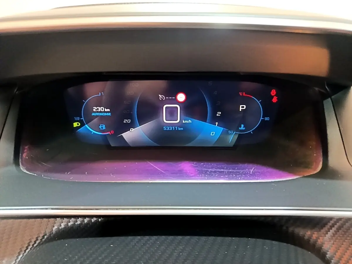 Tableau de bord numérique de Peugeot 208 jaune, affichage de la vitesse, autonomie et température moteur.