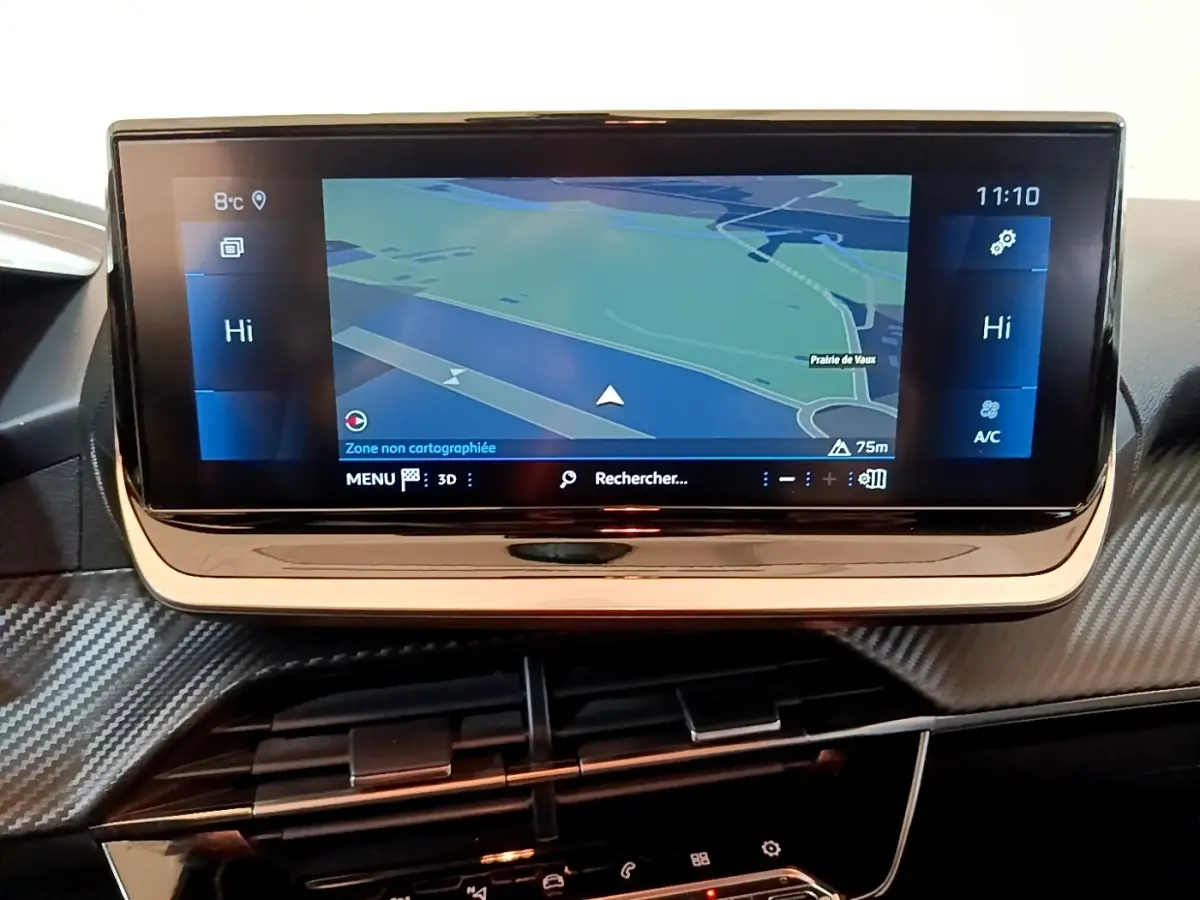 Écran tactile central de navigation affichant une carte, tableau de bord avec finition carbone dans une Peugeot 208.